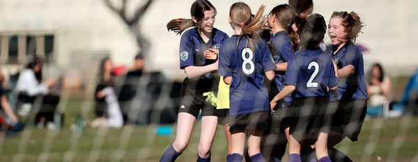 Region 13 teammates in navy uniforms celebrate after a goal