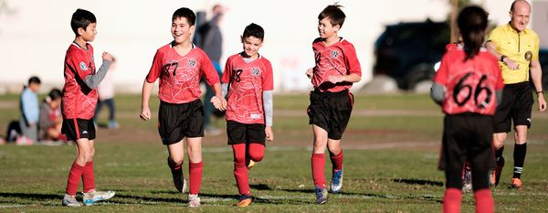 Region 13 boys in red and black uniforms walk off the field with a referee